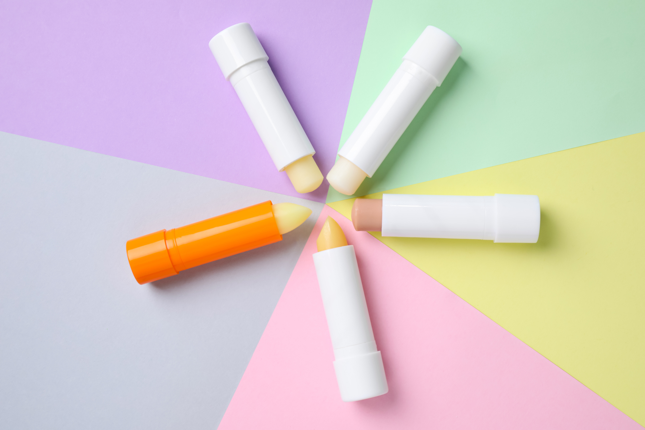 Five different lip balm tubes arranged in a circle in various colors