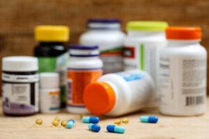 Several bottles of supplements and nutraceuticals set on a table with several pills and lozenges spread across the table