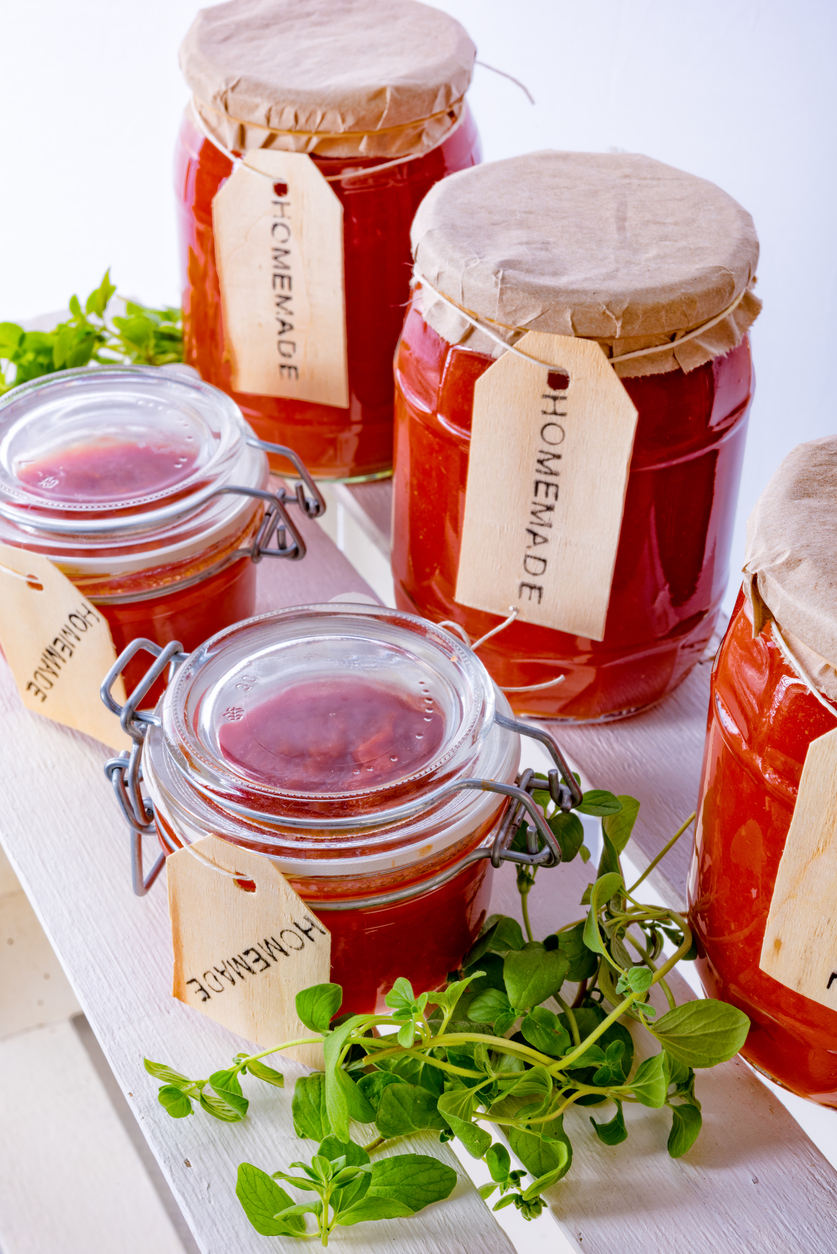 Mason jars on a farmer's market stand, each containing jam and complete with blank, homemade labels